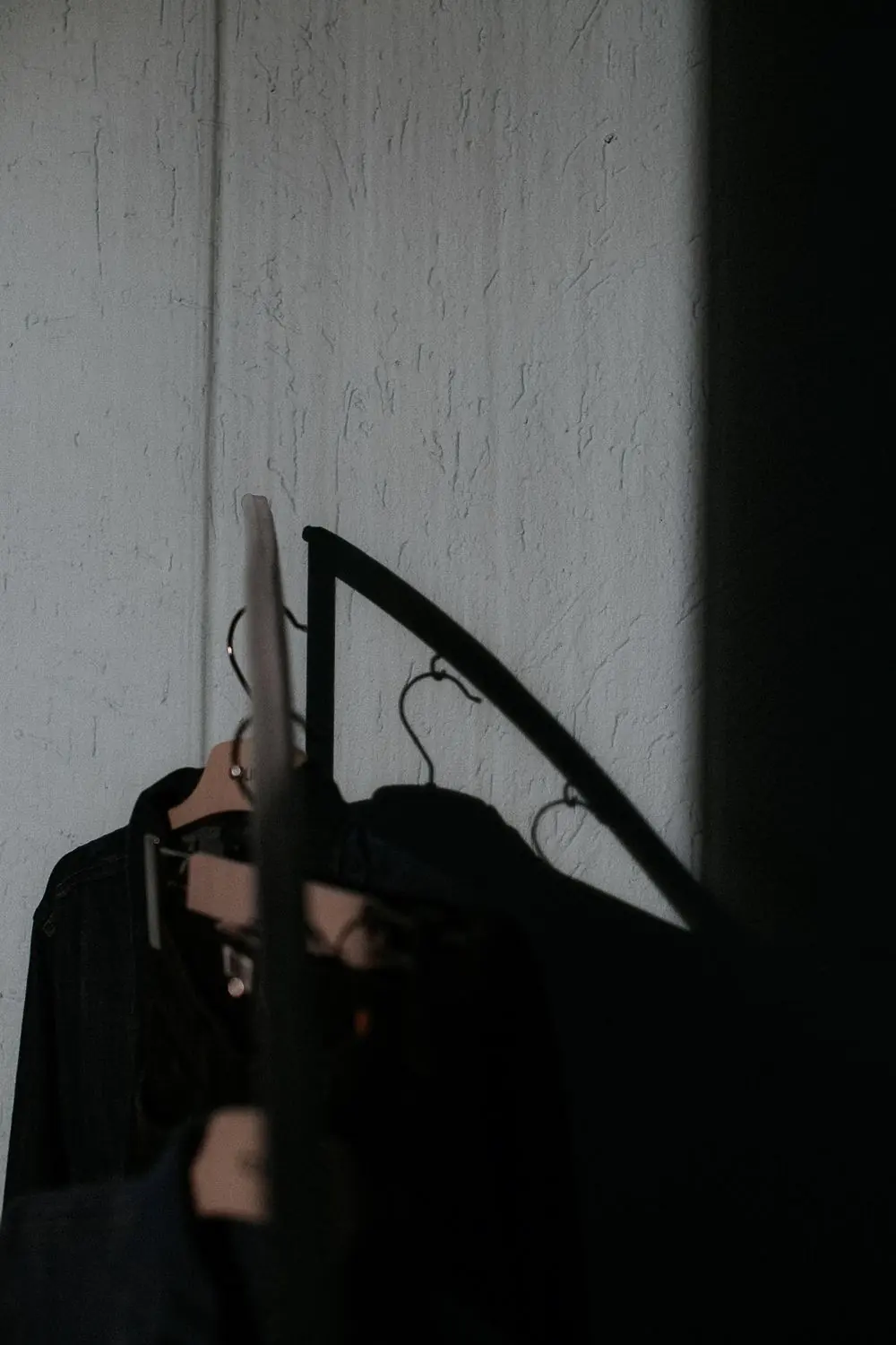 Reference photo 3: black garments on hangers in a dark interior — abayas & kaftans we manufacture and export in bulk to Qatar