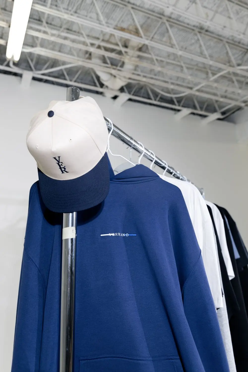 Reference photo 2: navy hoodie and cap on a rail — hoodies & sweatshirts we manufacture and export in bulk