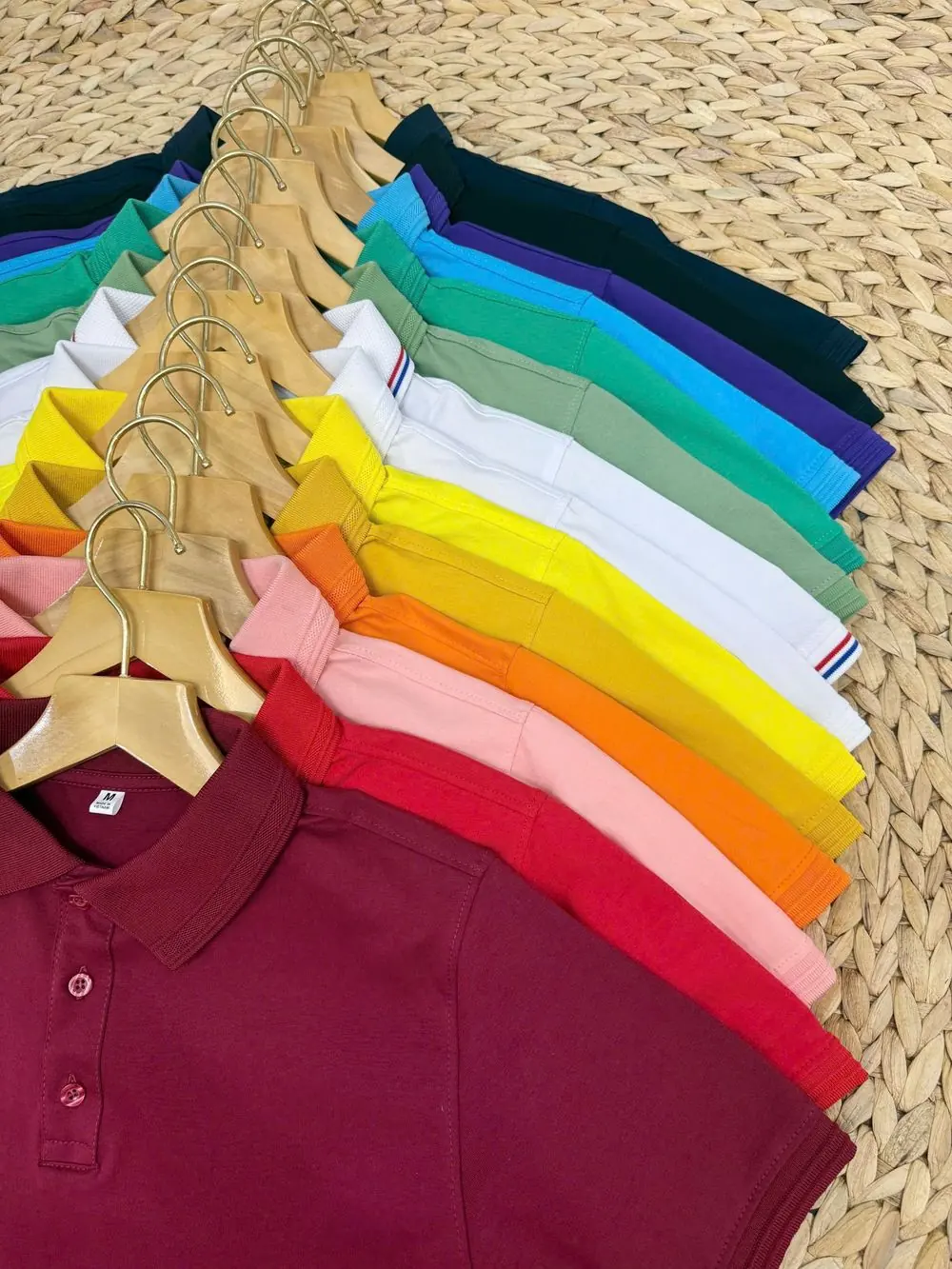 Reference photo 2: rainbow of polo shirts on hangers — polo t-shirts we manufacture and export in bulk to Tanzania